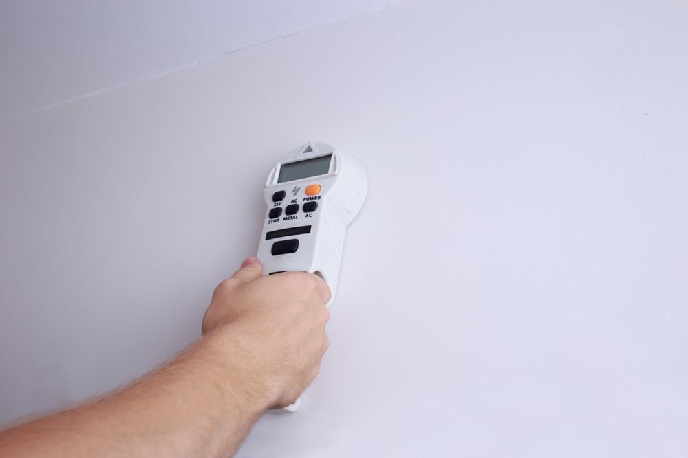A man's hand holding an electronic wall scanner