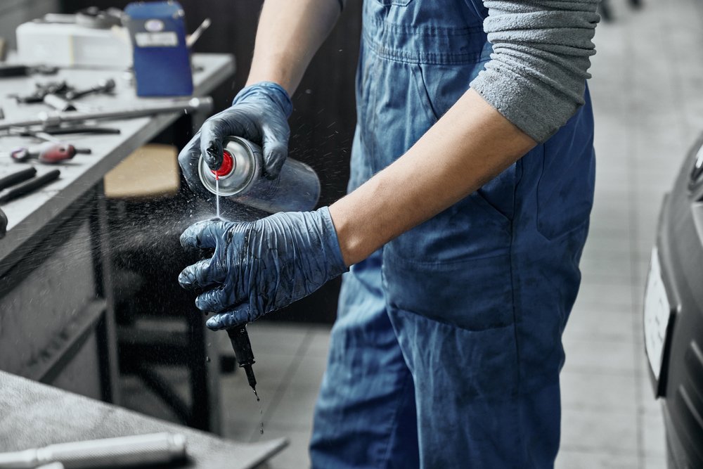 A mechanic spraying substance to spark plug
