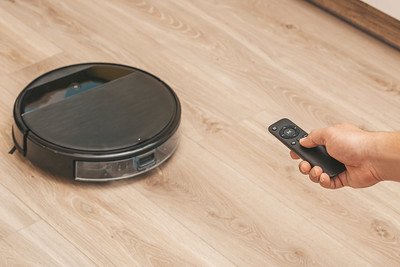 Close-up of a man holding remote control of a device to start cleaning