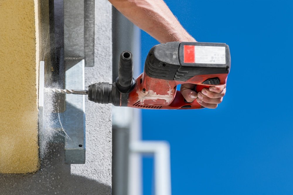 Hand holding cordless drilling machine.