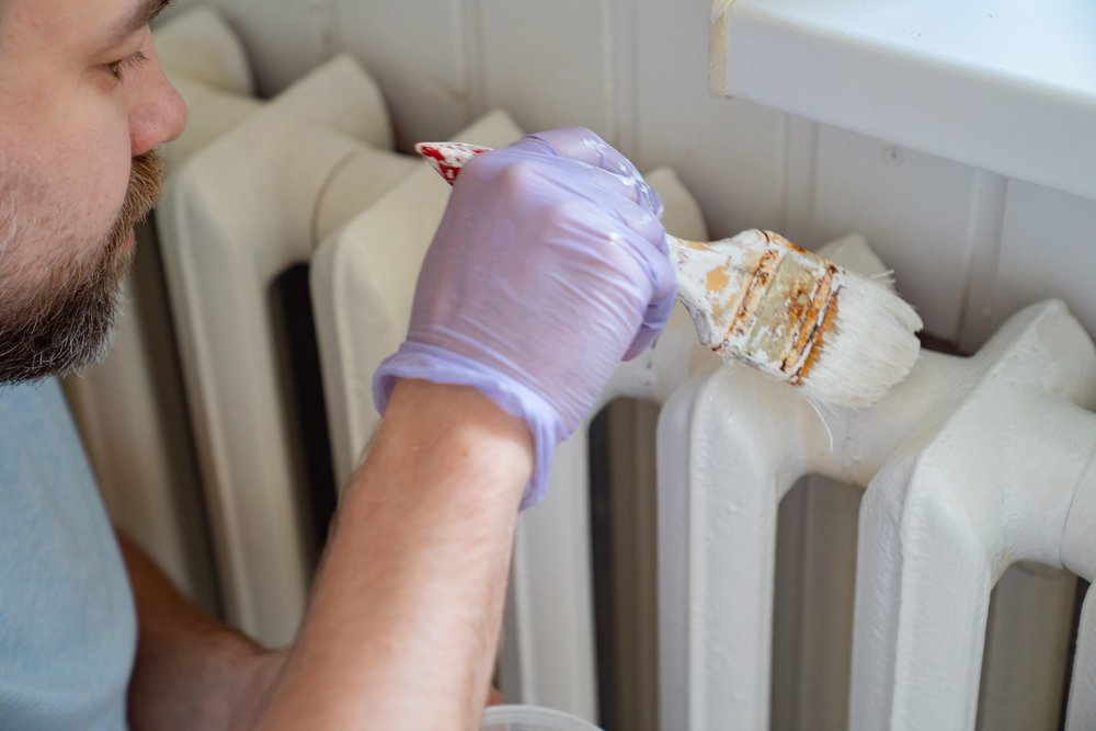 Man in a glove painting an equipment at home