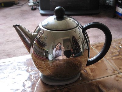 a woman taking a picture of a stainless steel kettle
