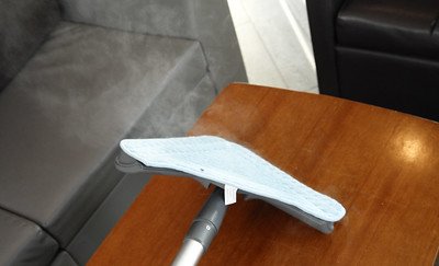 cleaning a wooden table with a steamer