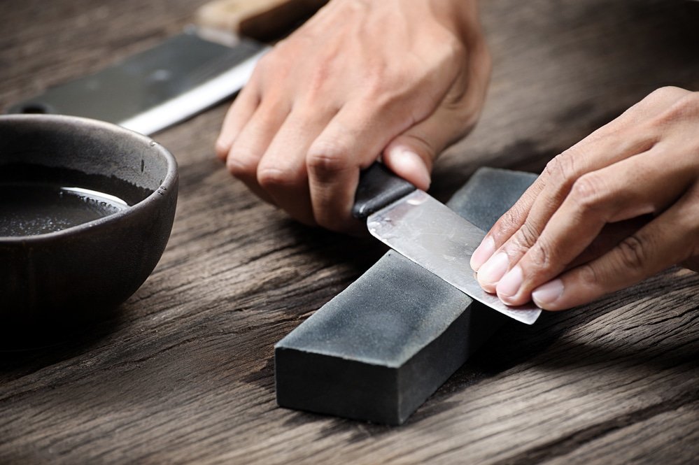a pair of hands smoothening the blades of a chopping tool