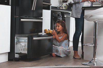 a little girl getting food from the refrigerator